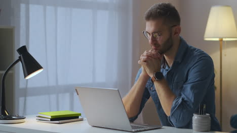 adult-man-is-viewing-learning-video-on-screen-of-notebook-self-education-by-internet-at-home-portrait-of-guy-with-glasses-at-table-in-room